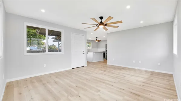 a view of empty room with wooden floor and fan