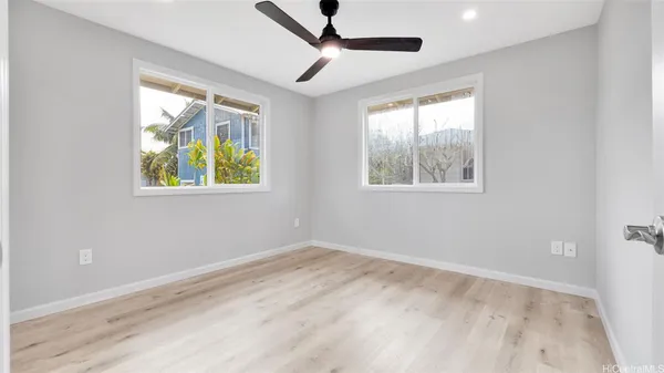 a view of an empty room with a window and wooden floor