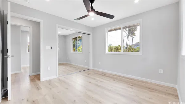 a view of an empty room with window and wooden floor