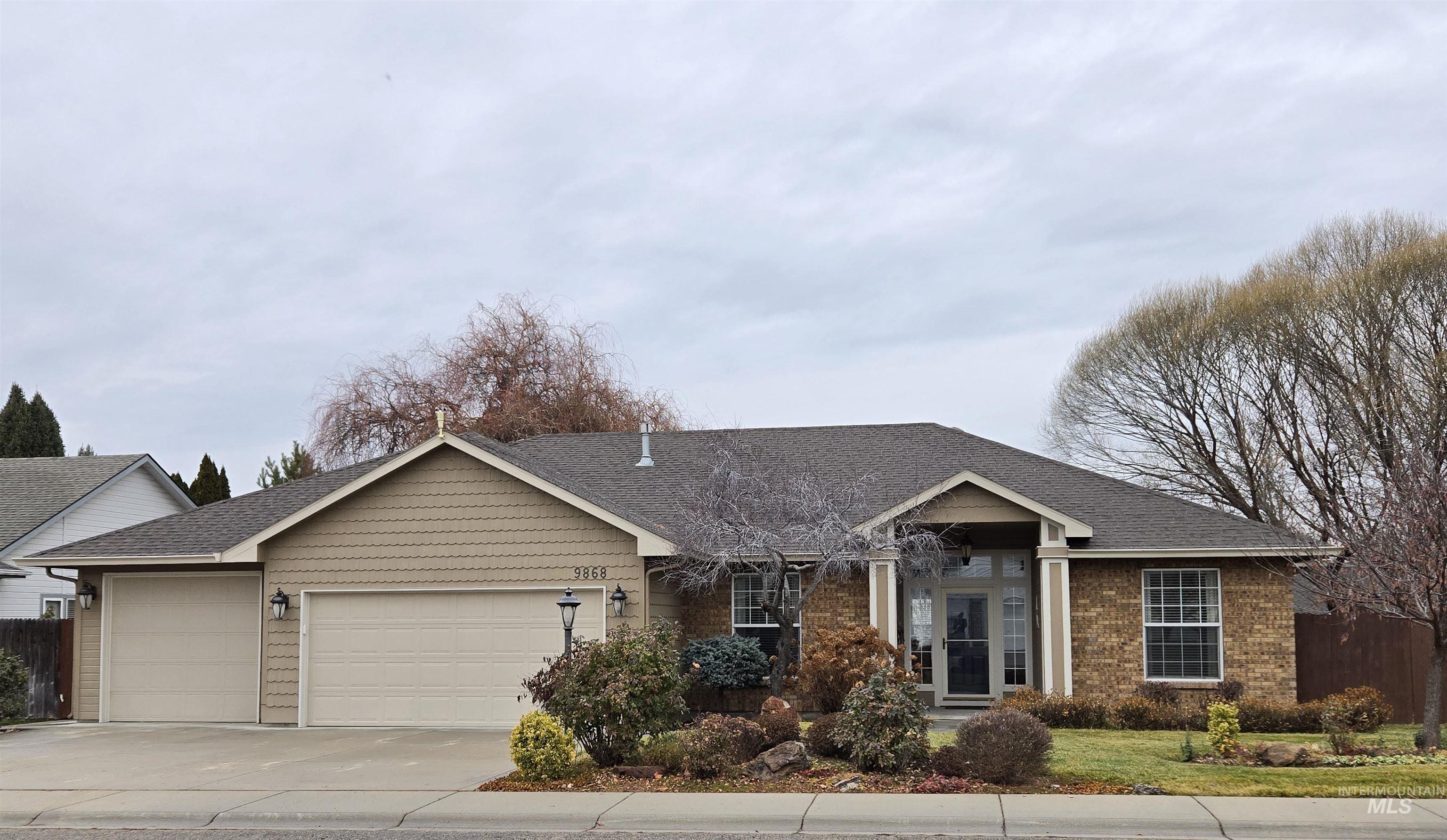 View of front of property with driveway, an attached garage, roof with shingles, and brick siding
