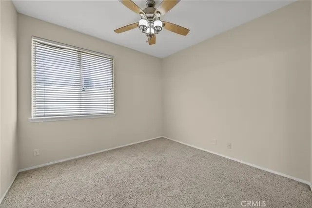 an empty room with a window and a fan