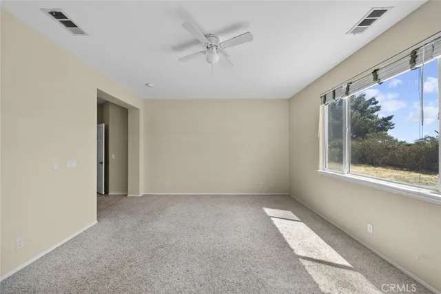 an empty room with a window and a ceiling fan