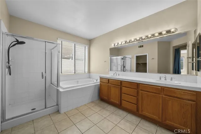 a spacious bathroom with a double vanity sink a large mirror and shower