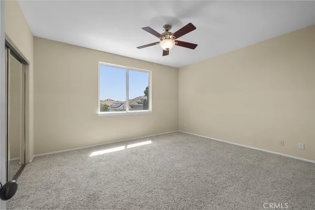 an empty room with window and ceiling fan