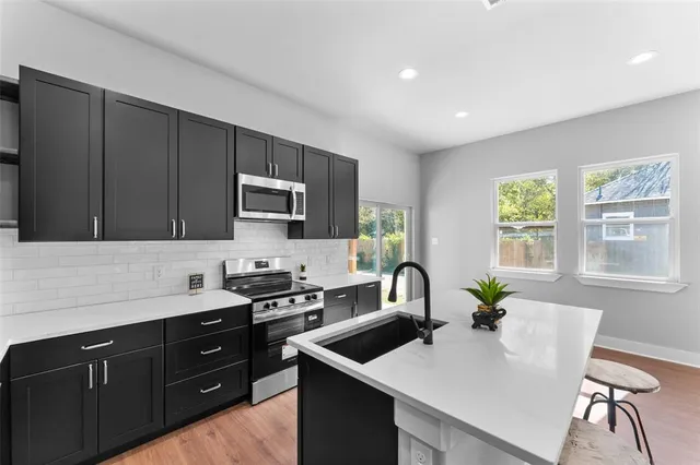 a kitchen with a stove a sink a microwave a dining table and chairs