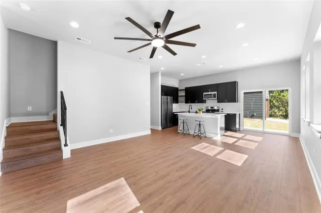a living room with furniture and kitchen view with a large window