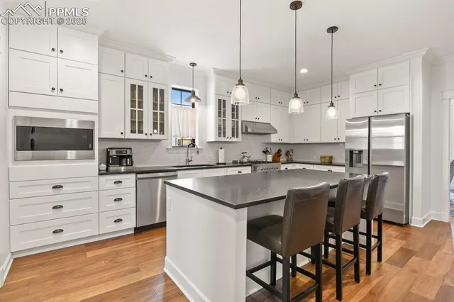 a kitchen with stainless steel appliances kitchen island granite countertop a table chairs and a sink