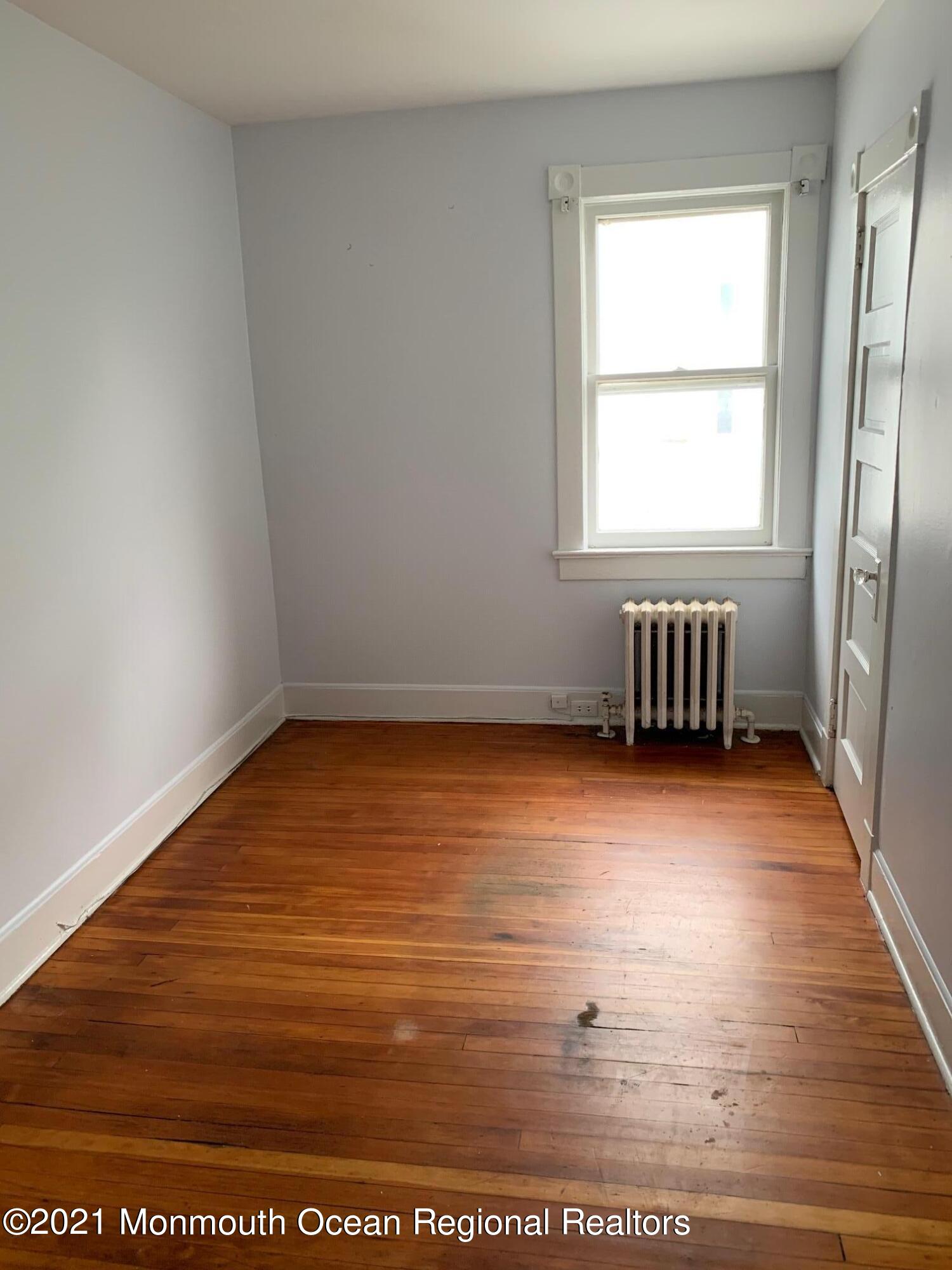 1428 6th Avenue Neptune, NJ 07753 - Photo 4 of 6 an empty room with wooden floor and windows