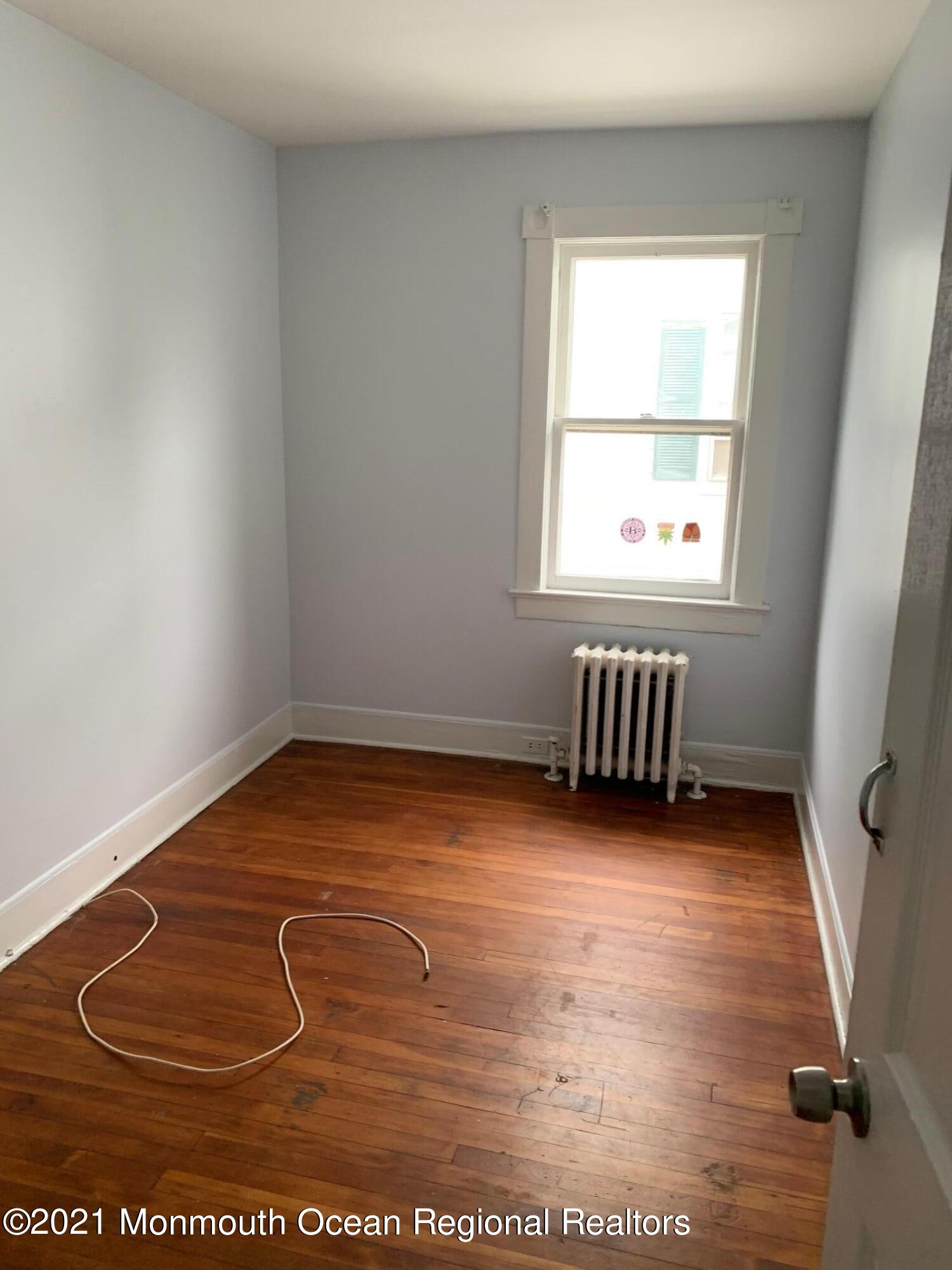 1428 6th Avenue Neptune, NJ 07753 - Photo 5 of 6 an empty room with wooden floor and windows