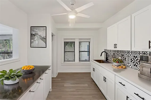 a view of an empty room with chandelier fan and wooden floor