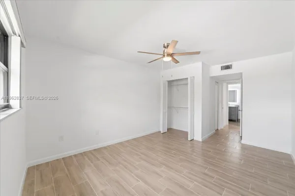 a view of a big room with wooden floor and a ceiling fan