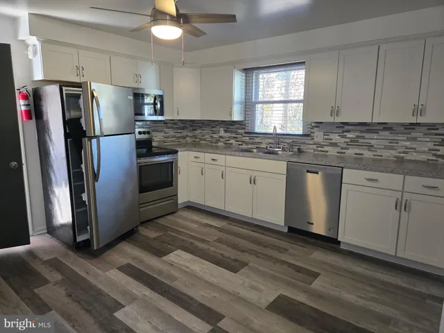 a kitchen with granite countertop a refrigerator sink and cabinets