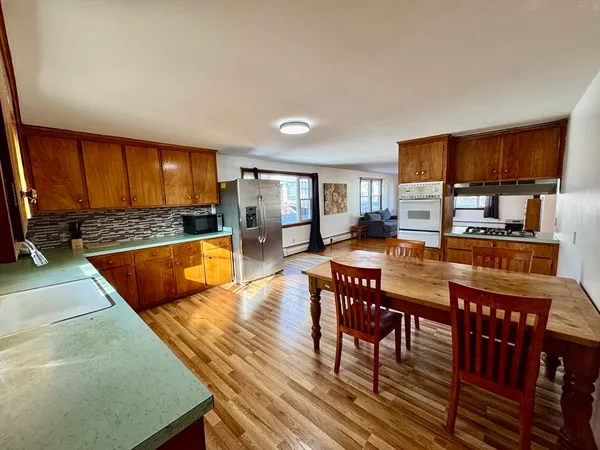 a kitchen with stainless steel appliances granite countertop a stove a sink a dining table and chairs