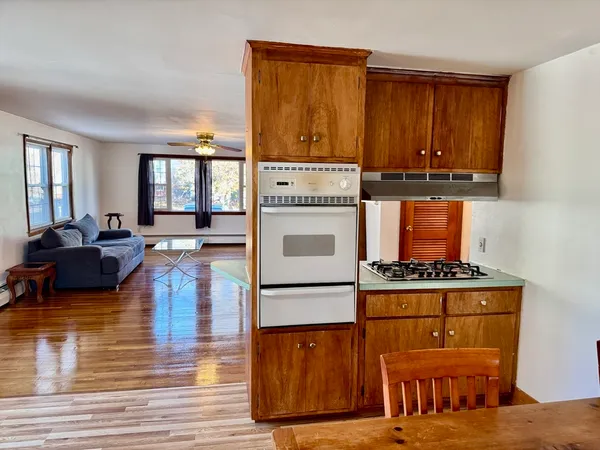 a living room with stainless steel appliances granite countertop wooden floors a stove and a window