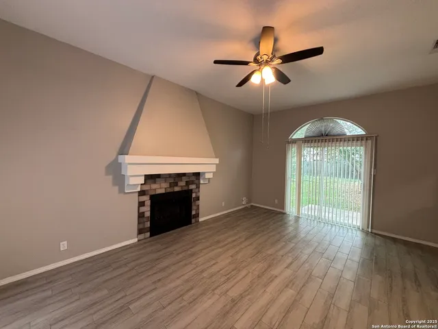 an empty room with wooden floor fireplace and windows