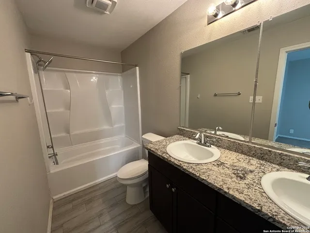 a bathroom with a granite countertop sink toilet a mirror and shower