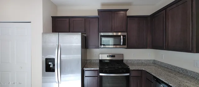 a kitchen with granite countertop wooden cabinets and stainless steel appliances