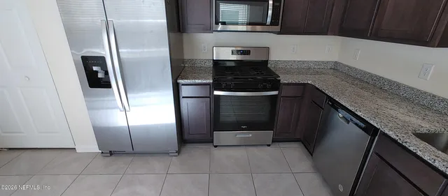 a kitchen with granite countertop a refrigerator and a stove
