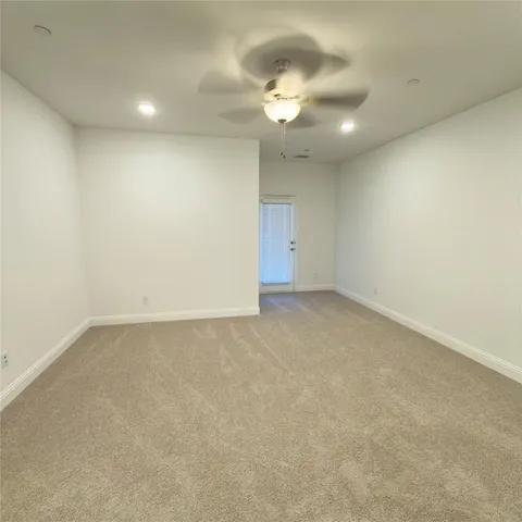 an empty room with a chandelier fan and windows