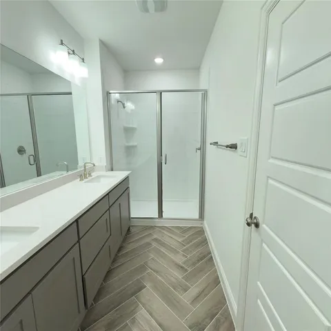 a bathroom with a double vanity sink mirror and shower