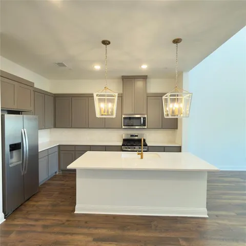 a large kitchen with kitchen island a counter space a sink appliances and cabinets