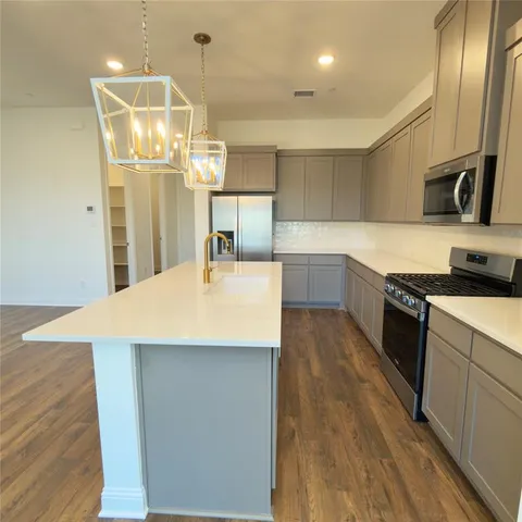a kitchen with stainless steel appliances a kitchen island hardwood floor sink and stove