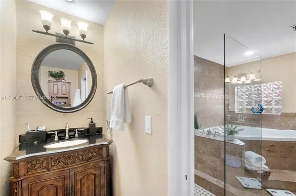 a bathroom with a sink a mirror a light fixture and a shower