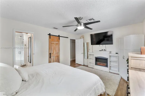 a bedroom with a large bed a flat tv screen and fireplace