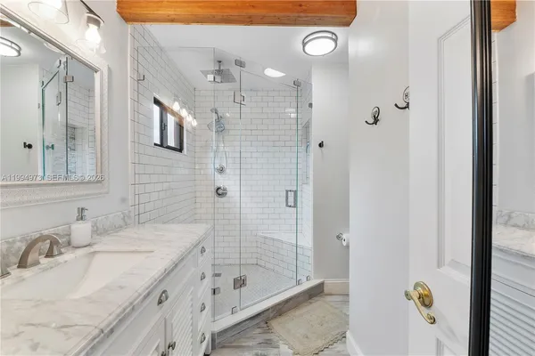 a bathroom with a granite countertop sink a mirror a bathtub and shower
