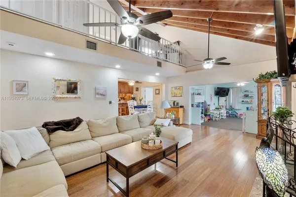 a living room with furniture kitchen view and a wooden floor