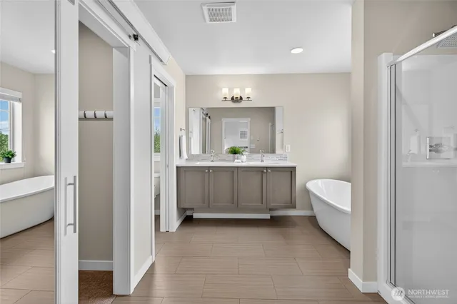 a bathroom with a double vanity sink a mirror a bathtub and shower