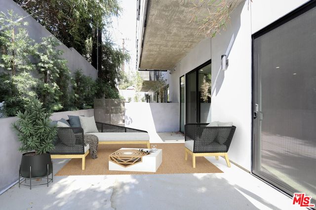 a view of a patio with table and chairs potted plants and large tree