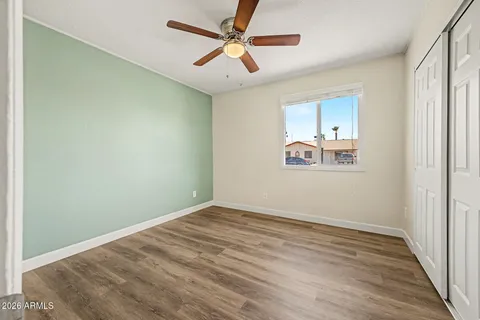 an empty room with wooden floor fan and windows