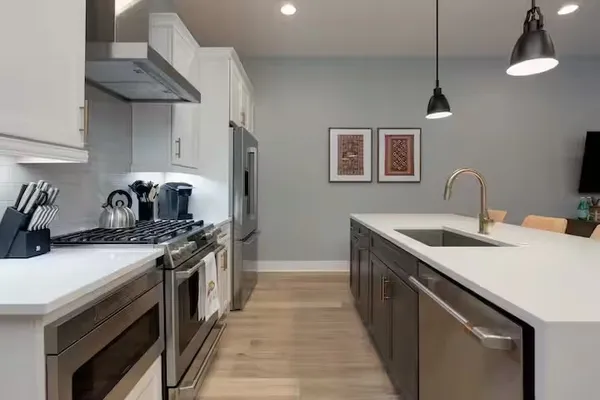 a kitchen with stainless steel appliances granite countertop a dining table chairs and a refrigerator