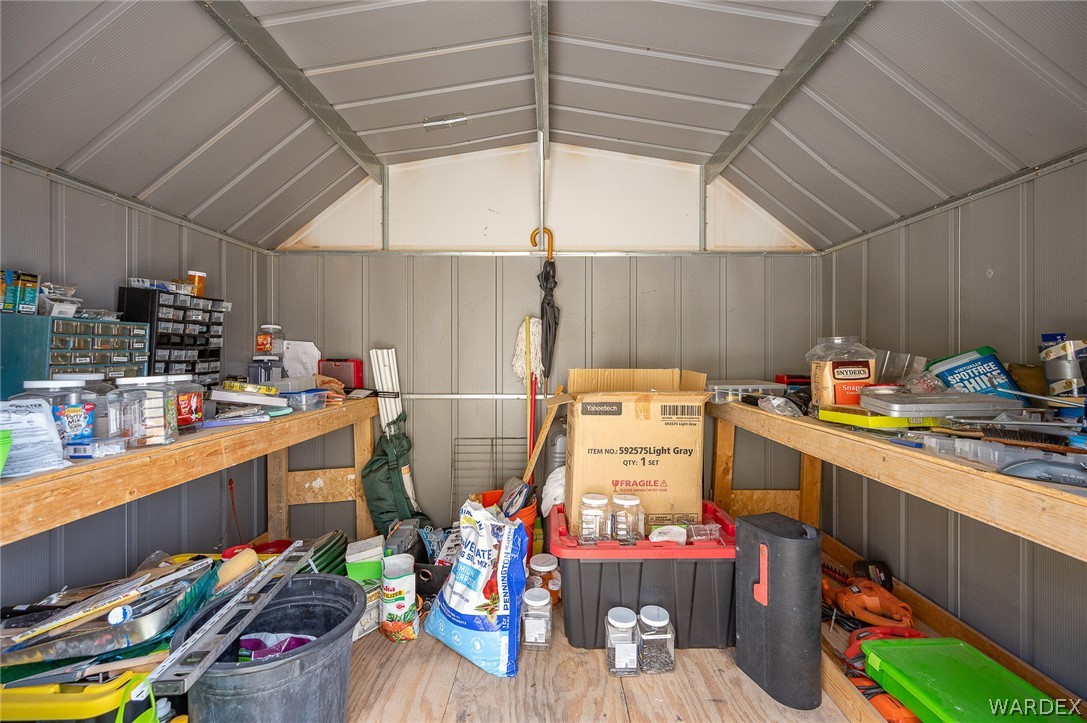 2465 Egar Road Golden Valley, AZ 86413 - Photo 53 of 98 The property includes an outdoor storage shed with a metal roof and panel siding, and wooden workbenches