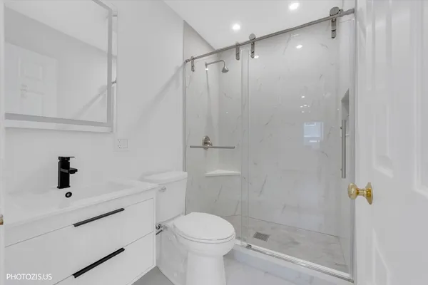 a bathroom with a shower sink vanity and toilet