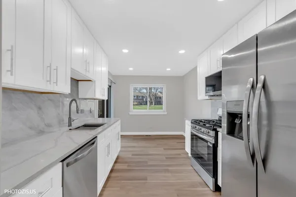 a kitchen with stainless steel appliances granite countertop a refrigerator a stove and a sink