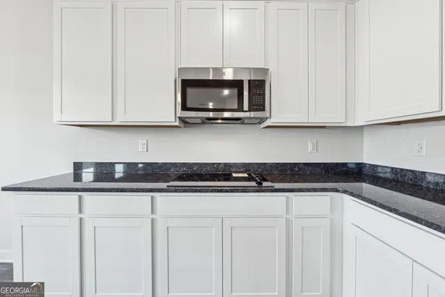 a kitchen with granite countertop white cabinets and a sink