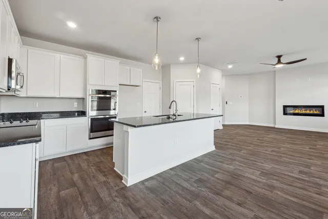 a large kitchen with kitchen island a sink a stove and white cabinets