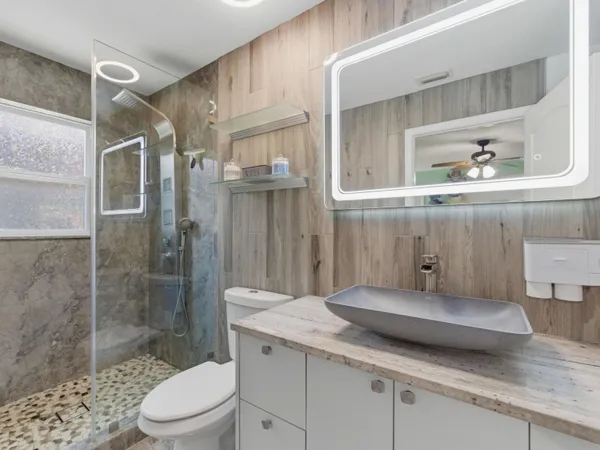 a bathroom with a granite countertop sink a toilet and shower