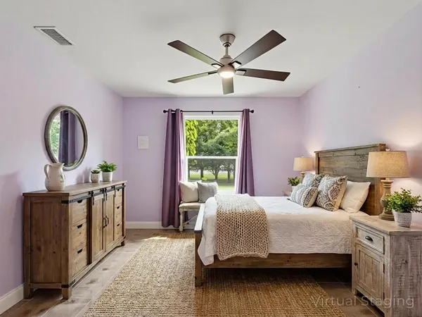 a bedroom with a bed a mirror on dresser and a large window