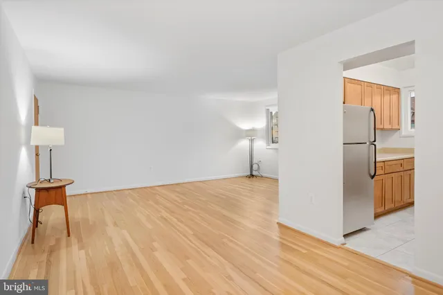 a view of a livingroom with wooden floor and a refrigerator