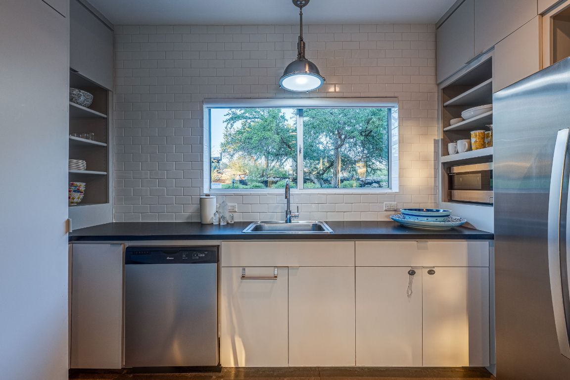 23601 Old Ferry Road, Unit 20 Spicewood, TX 78669 - Photo 21 of 40 a kitchen with granite countertop a sink and white cabinets