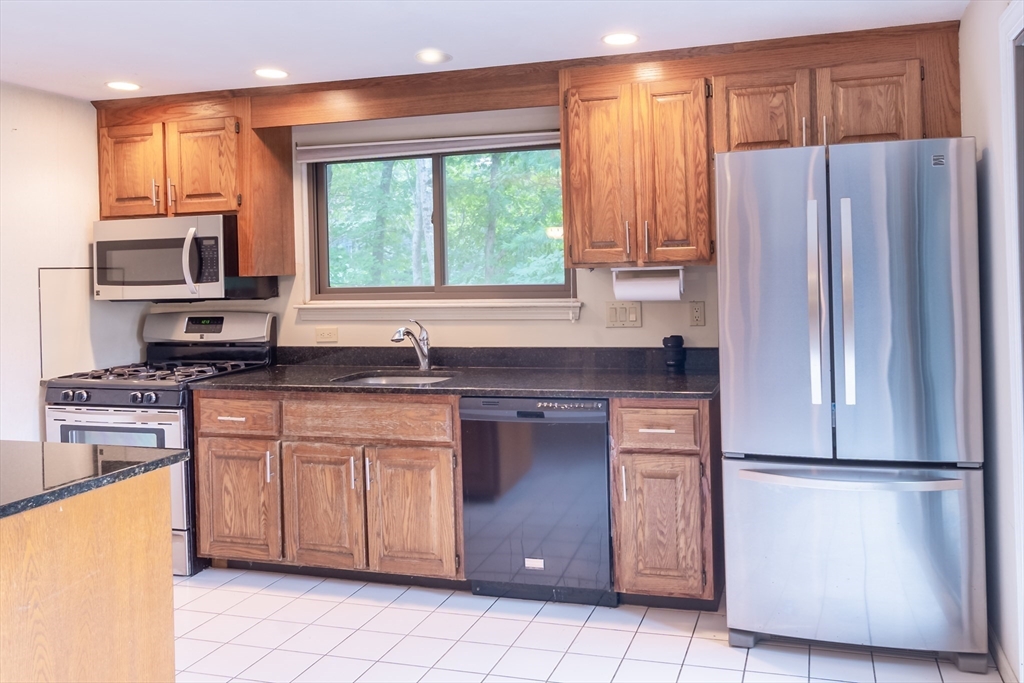 110 Mountain Gate Road, Unit 110 Ashland, MA 01721 - Photo 8 of 42 a kitchen with granite countertop stainless steel appliances a refrigerator cabinets and a window