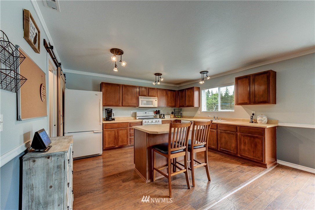 14155 Corbridge Road Southeast Monroe, WA 98272 - Photo 8 of 31 a view of kitchen with kitchen island stainless steel appliances refrigerator stove dining table and chairs