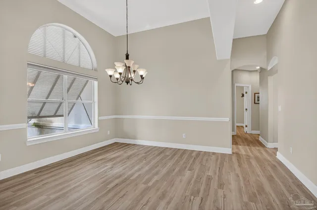 a dining hall with stainless steel appliances granite countertop a refrigerator a stove a oven and a dining table with wooden floor