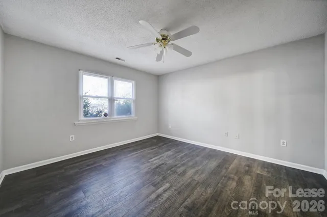 an empty room with wooden floor ceiling fan and windows