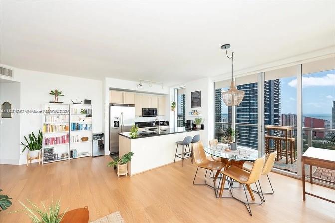 79 Southwest 12th Street, Unit 3601S Miami, FL 33130 - Photo 4 of 27 a kitchen with stainless steel appliances kitchen island granite countertop a refrigerator a stove a dining table and chairs with wooden floor