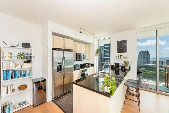 a kitchen with stainless steel appliances granite countertop a refrigerator a stove and a sink with wooden floor