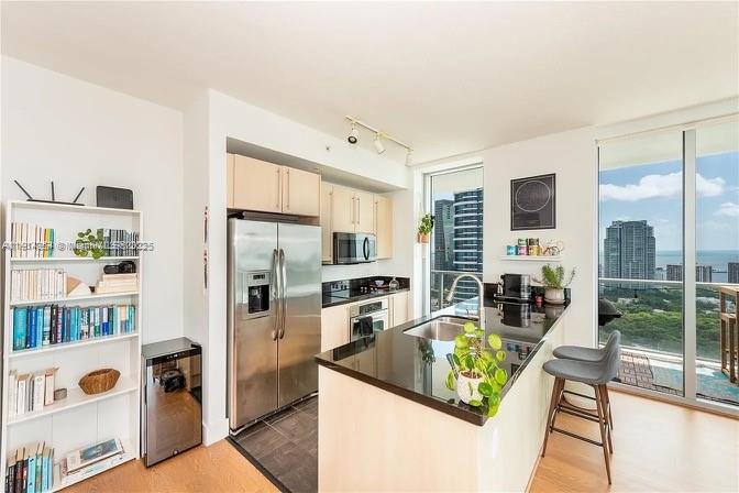79 Southwest 12th Street, Unit 3601S Miami, FL 33130 - Photo 7 of 27 a kitchen with stainless steel appliances granite countertop a refrigerator a stove and a sink with wooden floor
